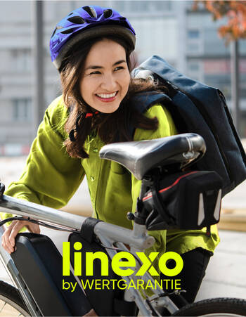 Eine Frau mit Fahrradhelm steht lächelnd vor ihrem Rad